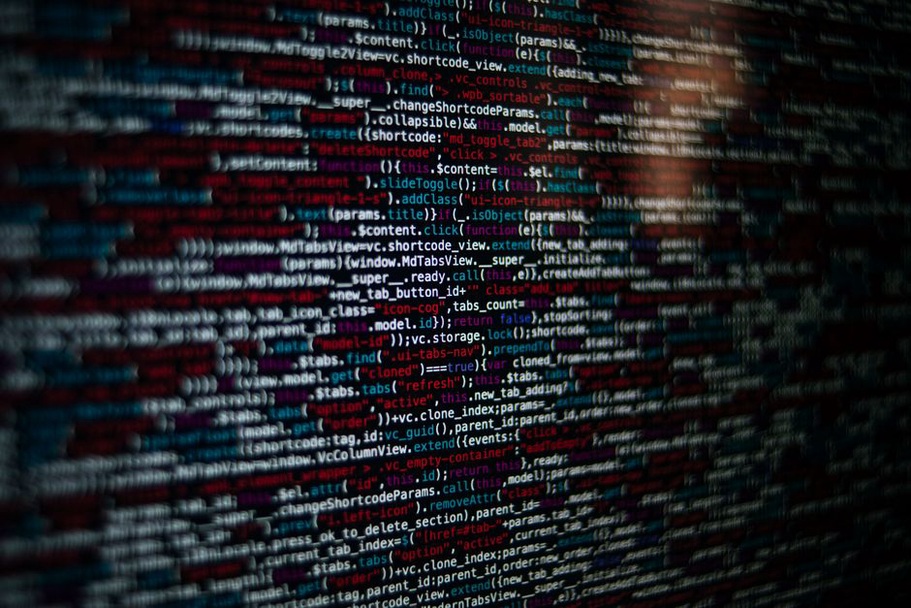 A monitor displays a PHP-generated table of conference sessions with paper titles and authors
